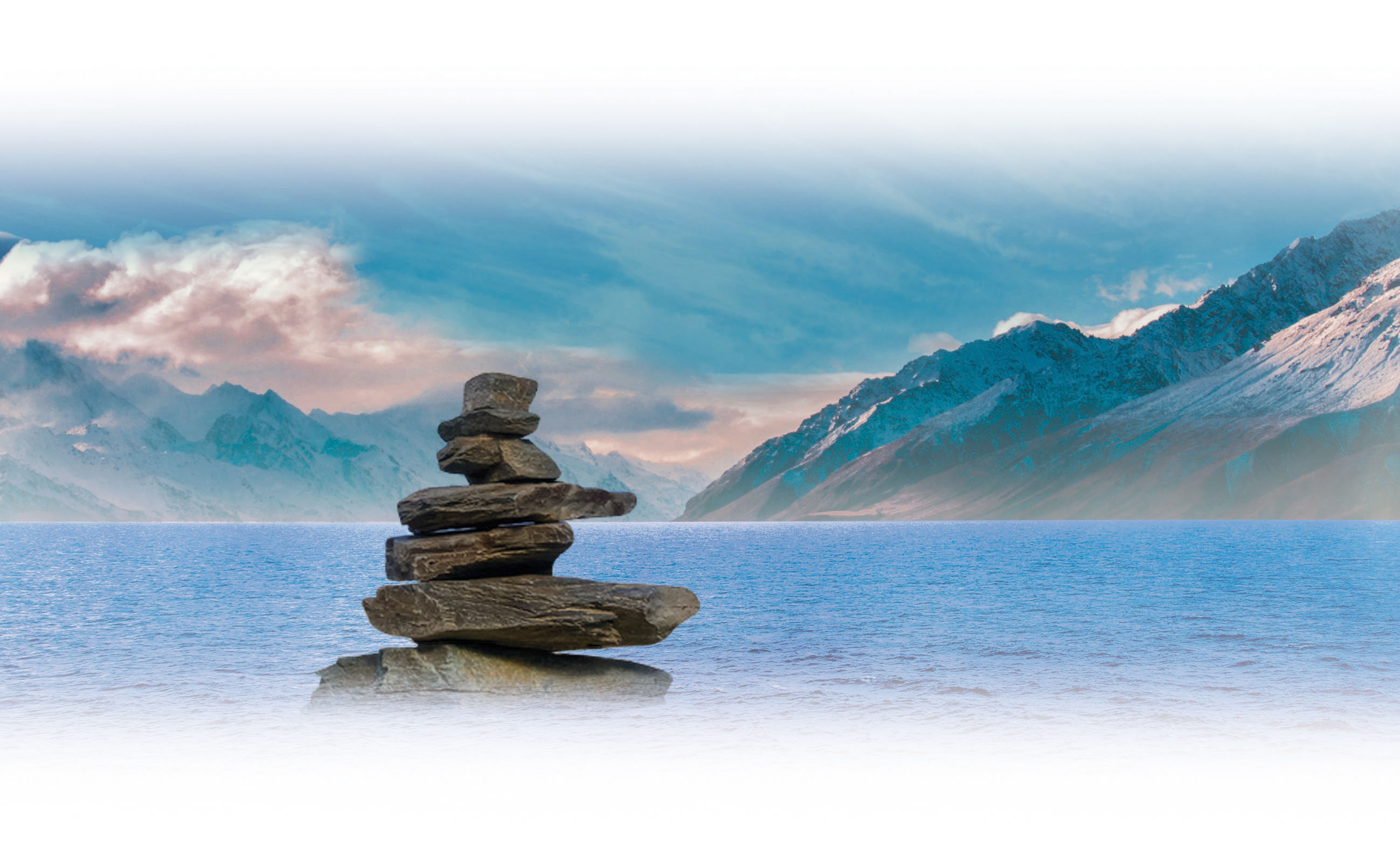 Gestapelte steine vor einer wunderschönen Landschaft bestehend aus Meer und bergen 
